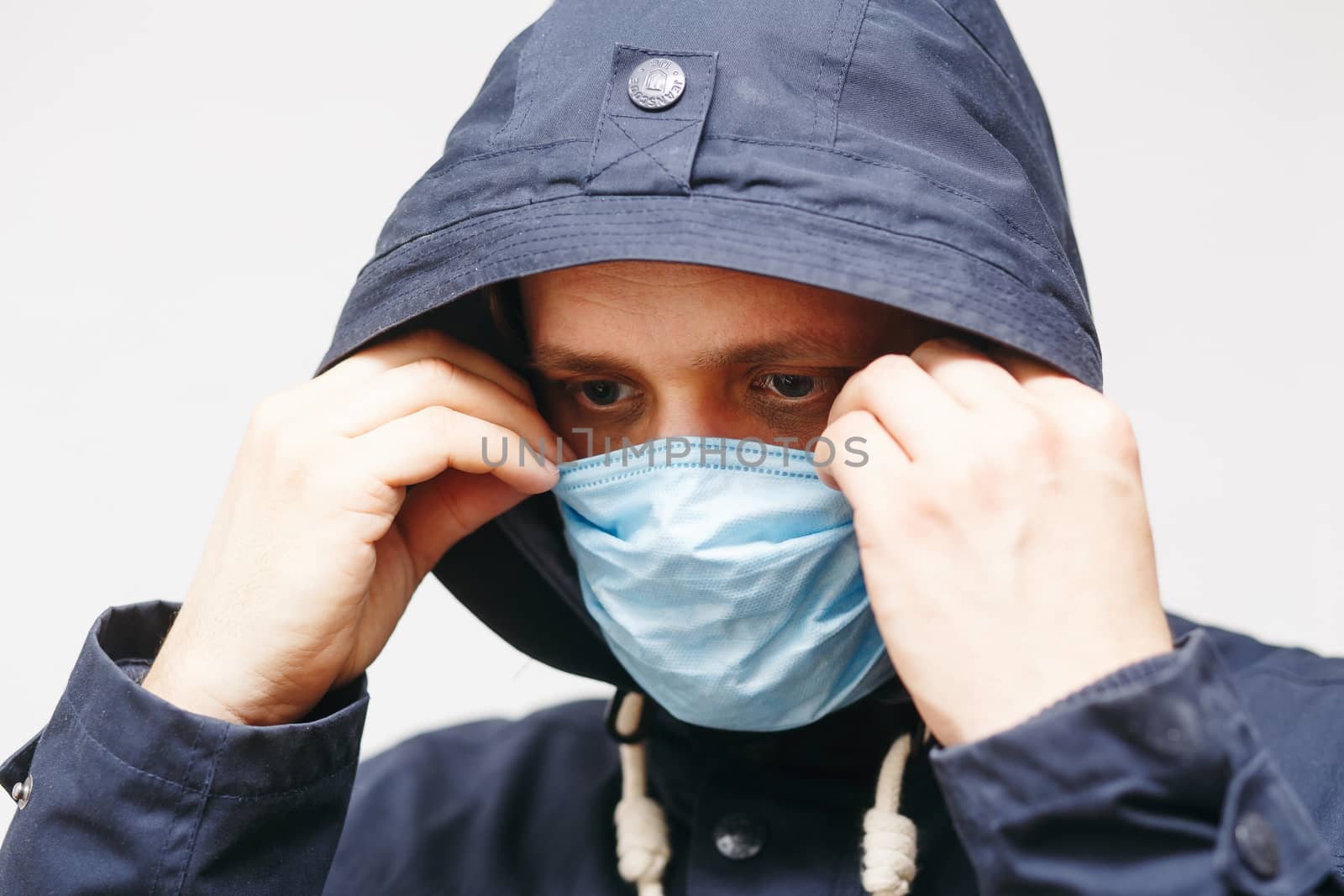 Man in hood with mask to protect him from Coronavirus. Corona virus pandemic. Young man with medical mask isolated. Person in hood with medical mask. COVID 19