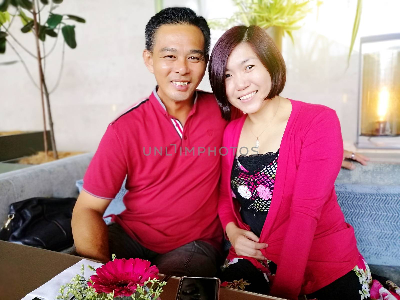 An Asian middle age attractive couple  sit in a beautiful cafe in the daytime.