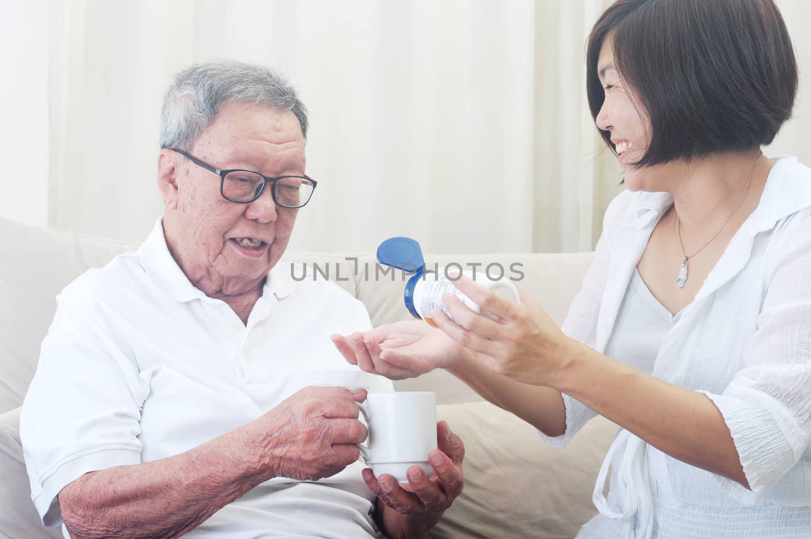 Asian senior man having medicine at home. Daughter take care of her father. 