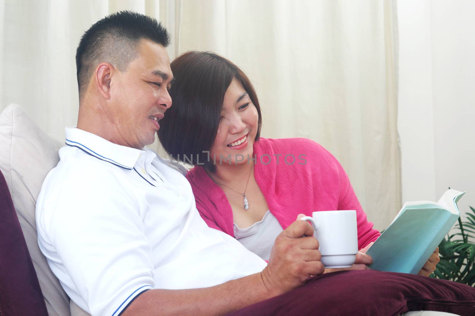 Happy Asian Middle age couple looking at the book and relaxing with a cup of coffee