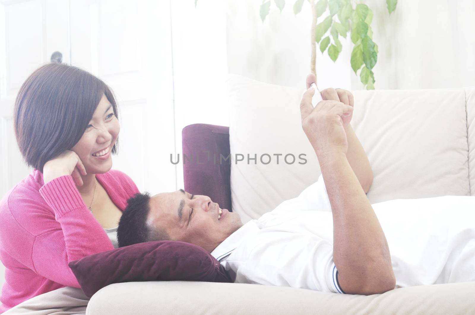 Happy Asian Middle age couple  having entertainment using smartphone at home