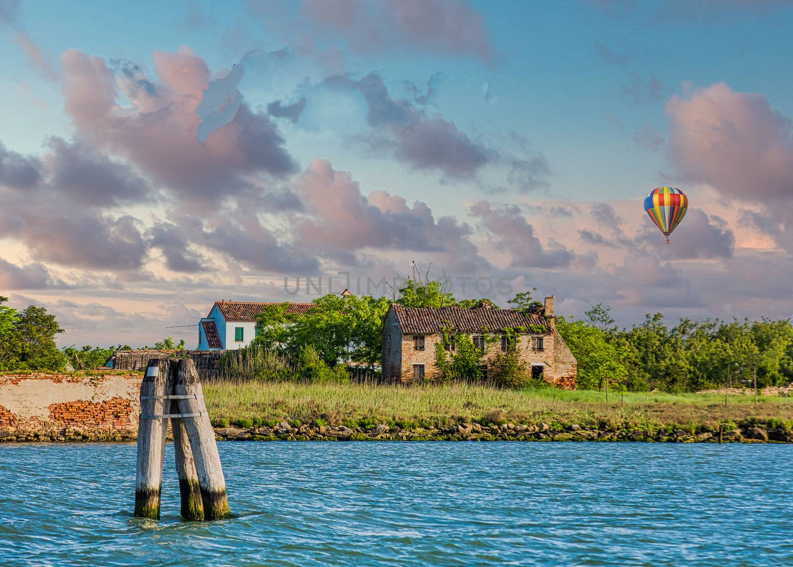 Old buildings on the edge of a large canal near Venice, Italy at dusk with hot air balloon