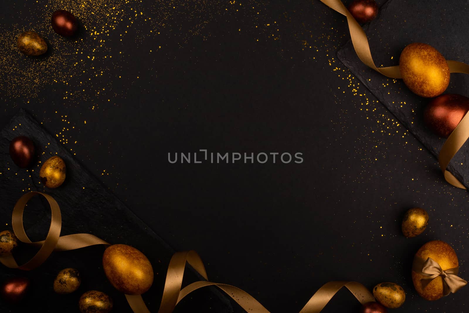 Golden luxury easter eggs and ribbon composition boder frame on black stone background with copy space for text card