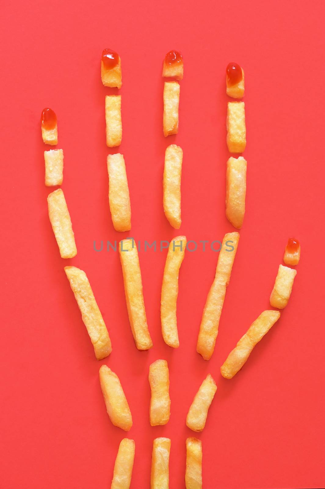 Human Hand  Concept With French Fries on Red Background