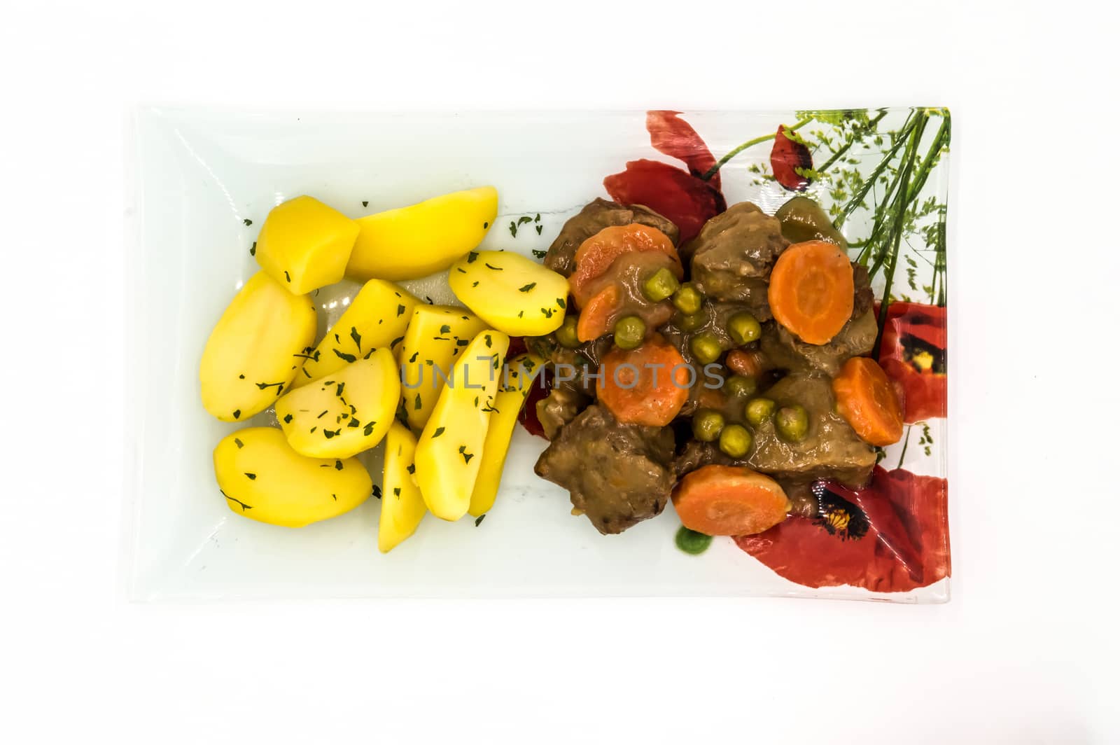 Belgian beef stew in beer with carrots and peas served on a glass plate with flowers