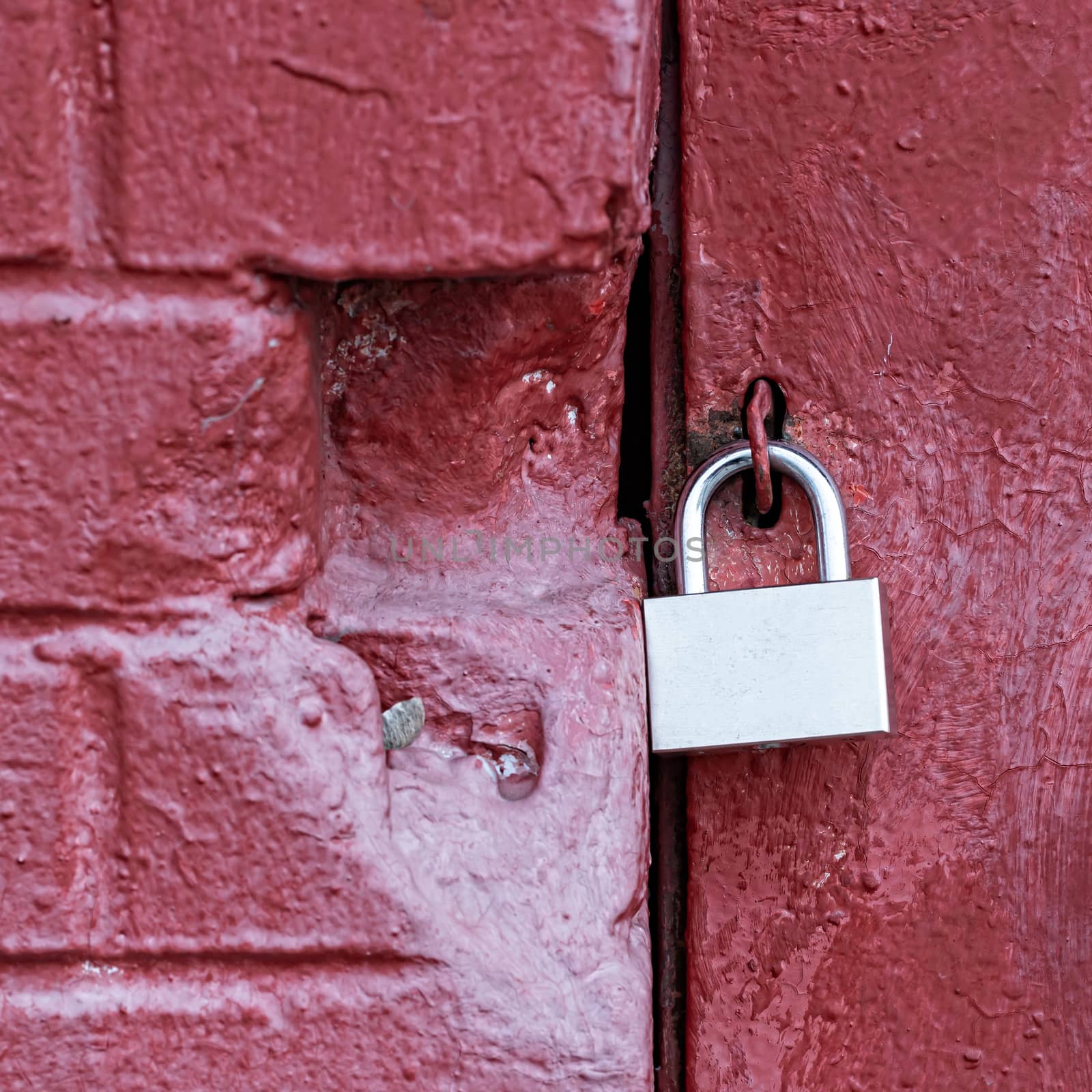 A silver padlock locks the old doors securely. Close- up view. by bonilook