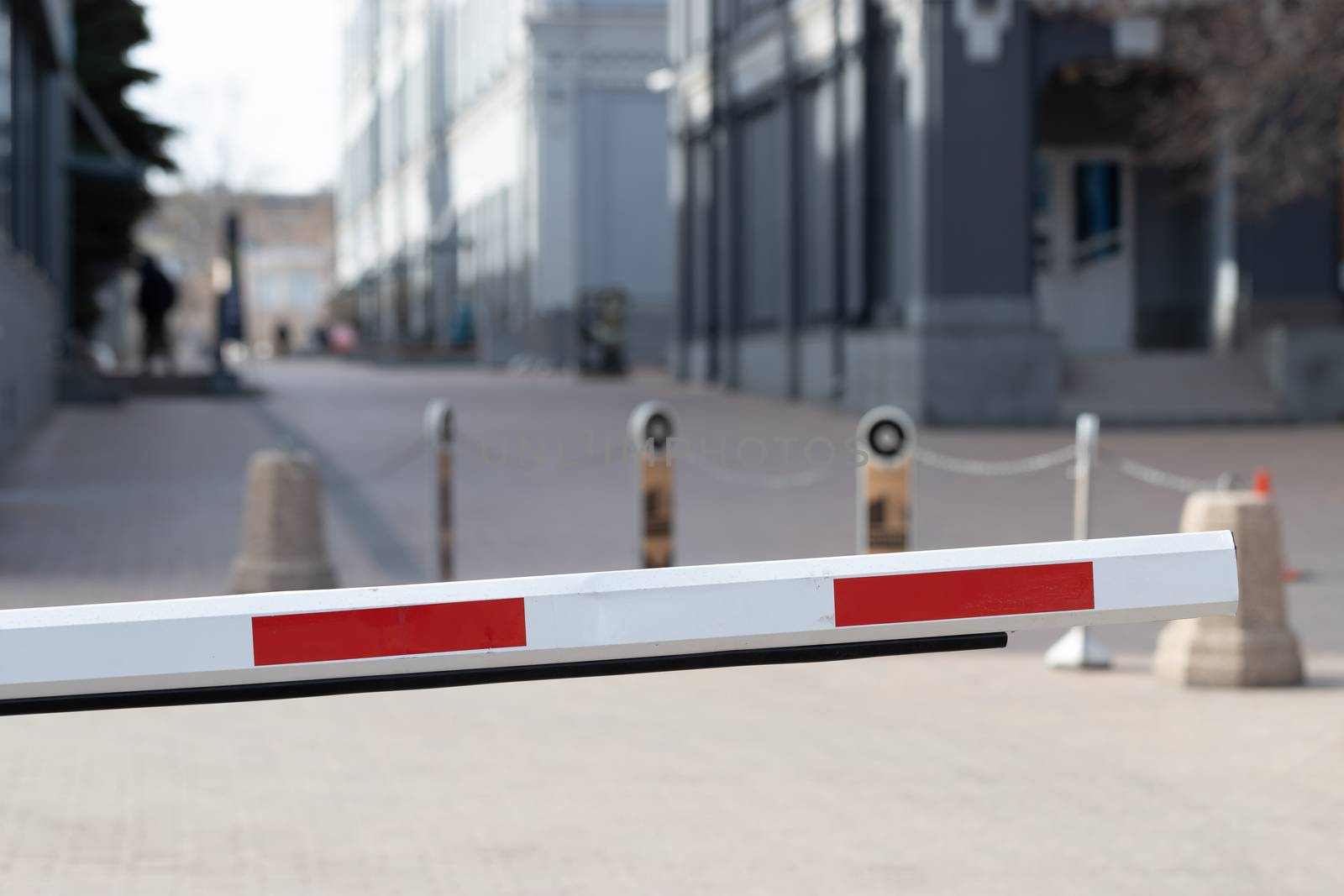 Automatic security metal barrier boom closed for stop and checking car entering to restricted area , placed at main entrance beside the road , selective focused, blurred background. Security concept or ban