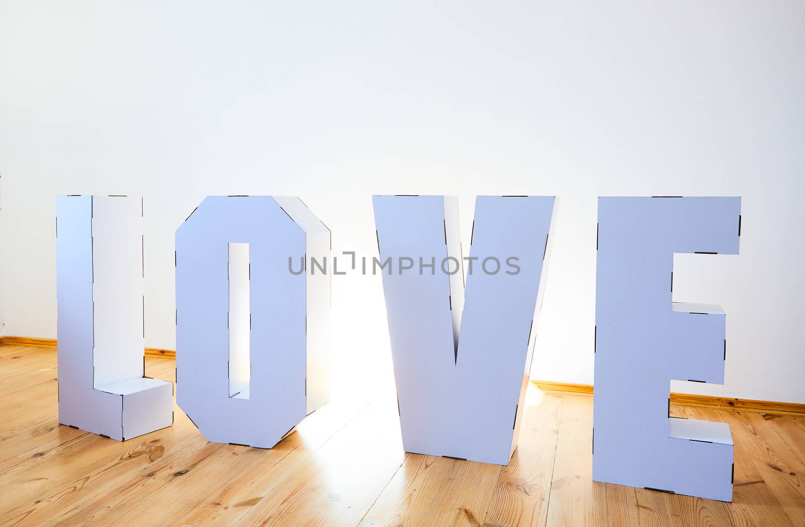 3D Standing Letters forming word LOVE from white cardboard on a light background. Relationship concept