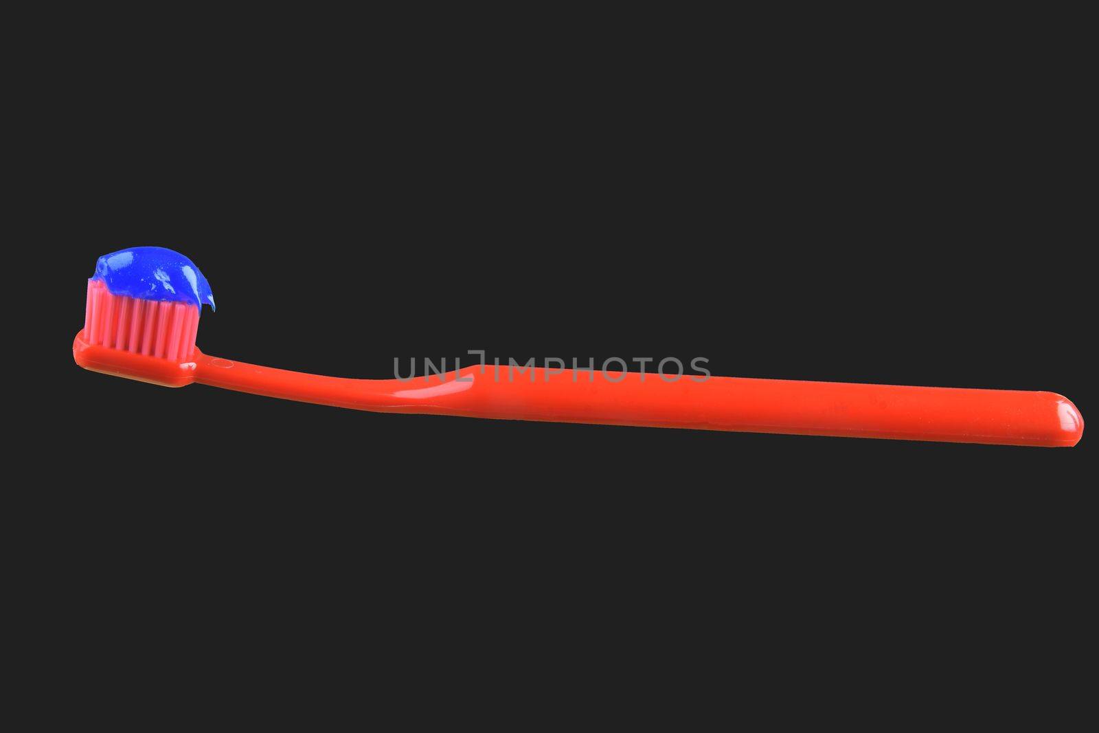 Red toothbrush and blue toothpaste isolated on the black background. by roman_nerud