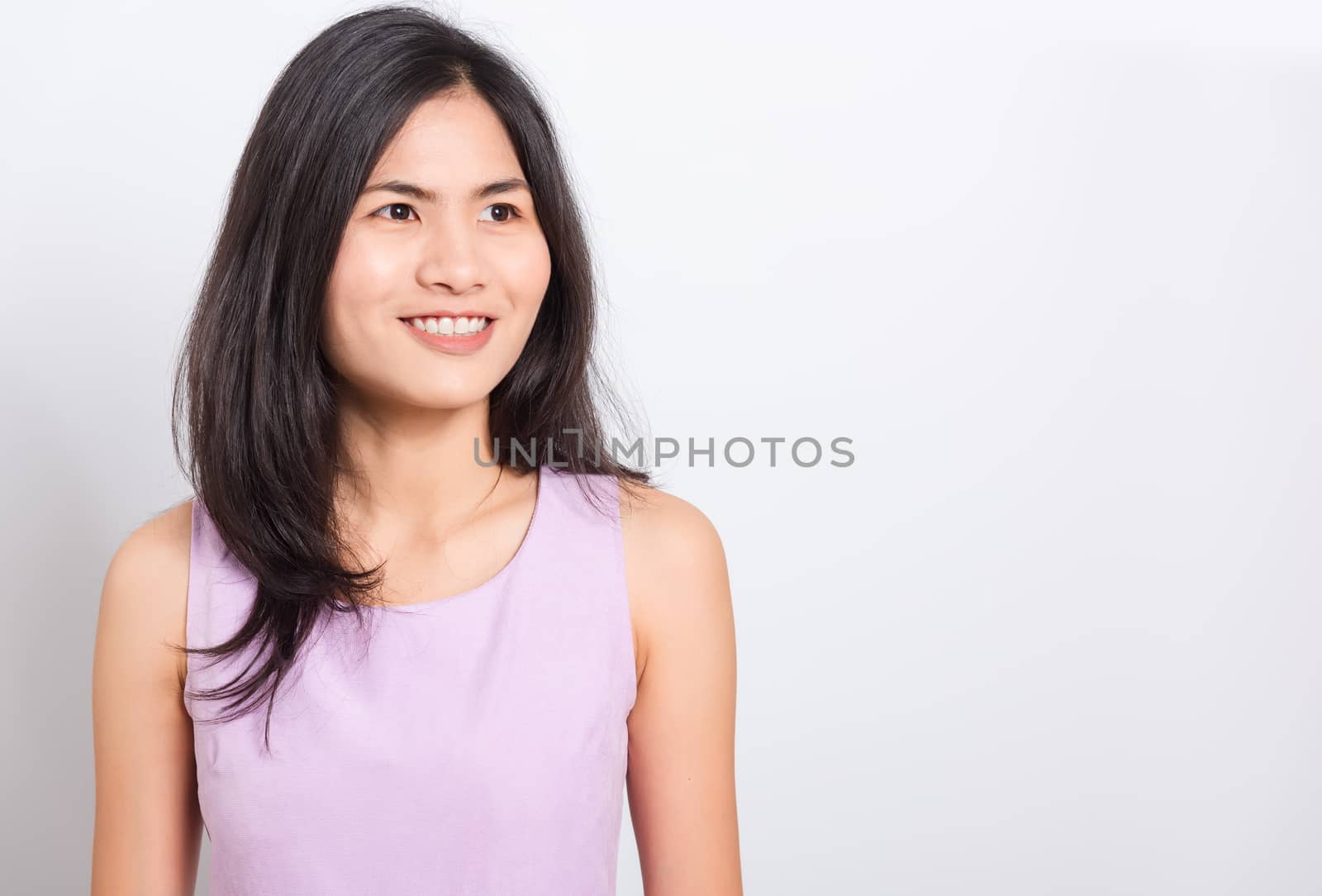Portrait Asian beautiful young woman standing smile seeing white teeth, She looking at the camera, shoot photo in studio on white background. There was a copy space to put text on the right-hand side.