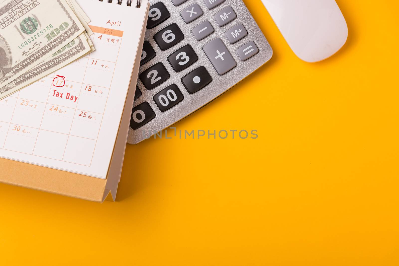 April of the year is Tax Day, Top view flat lay closeup calculator, laptop computer, calendar, and Dollar money, on yellow background business finance budget concept with copy space for text