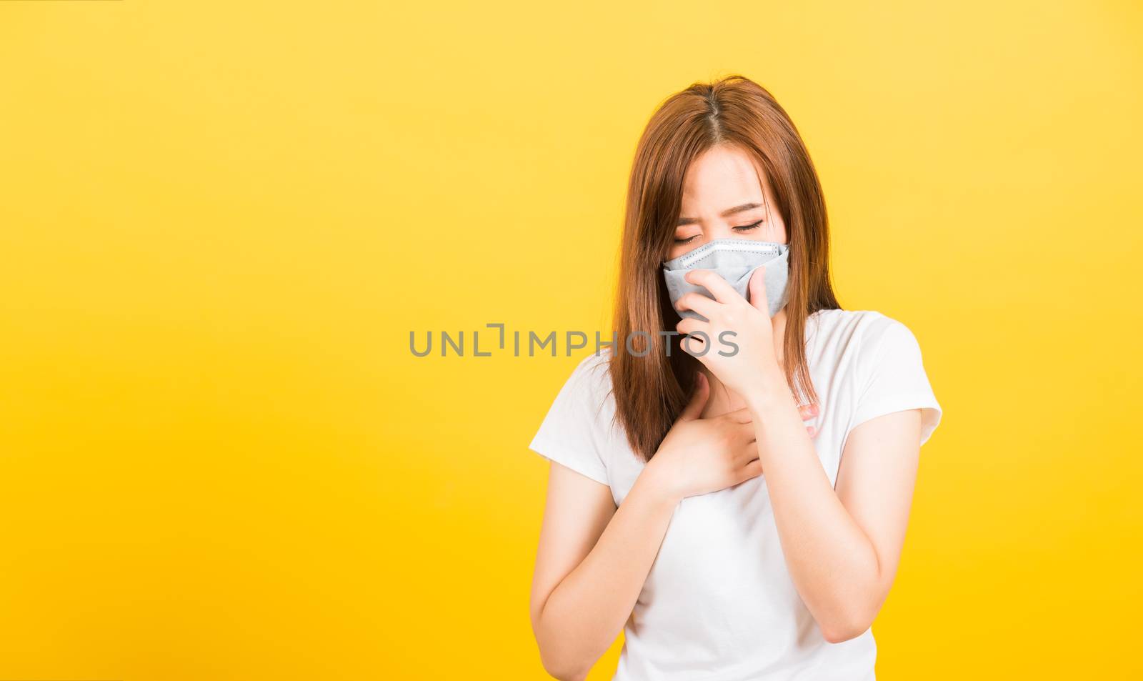 Asian happy portrait beautiful cute young woman teen standing wear t-shirt cough in mask protection from virus epidemic or air pollution isolated, studio shot on yellow background with copy space