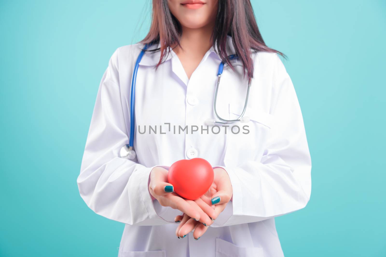 Asian doctor, beautiful young woman standing, smiling, holding a red head on hand on blue background with copy space for text Medical health care staff service concept