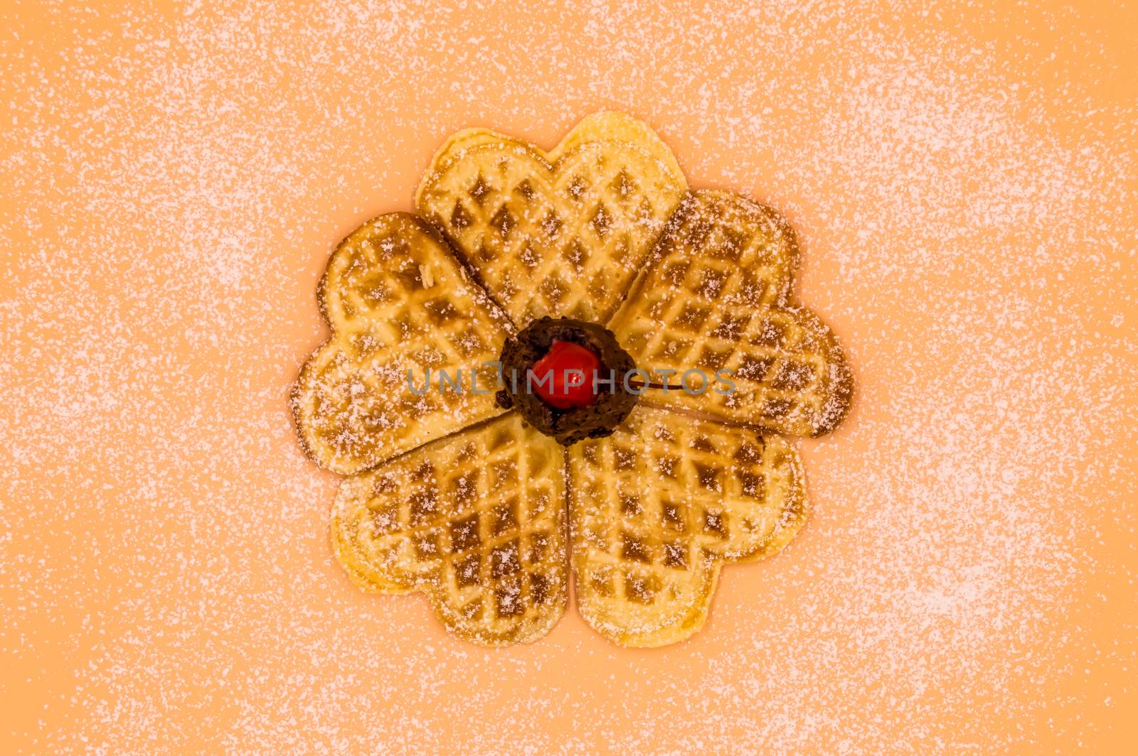 Homemade waffles with powdered sugar, a scoop of vanilla ice cream and a cherry on a pink background, isolated image of food.