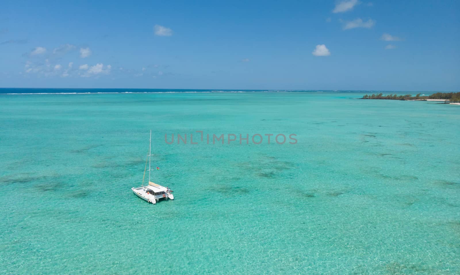 Catamaran sailing boat in turquoise sea lagoon on tropial Mauritius island. Aerial, top down drone view.