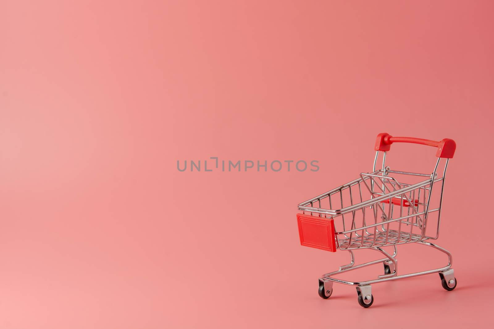 Shopping concept : Red shopping cart on pink background with copy space