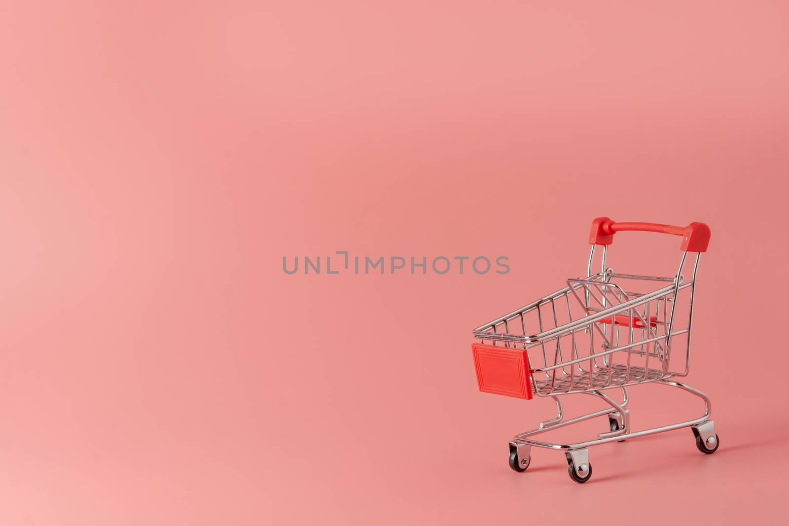 Shopping concept : Red shopping cart on pink background with copy space