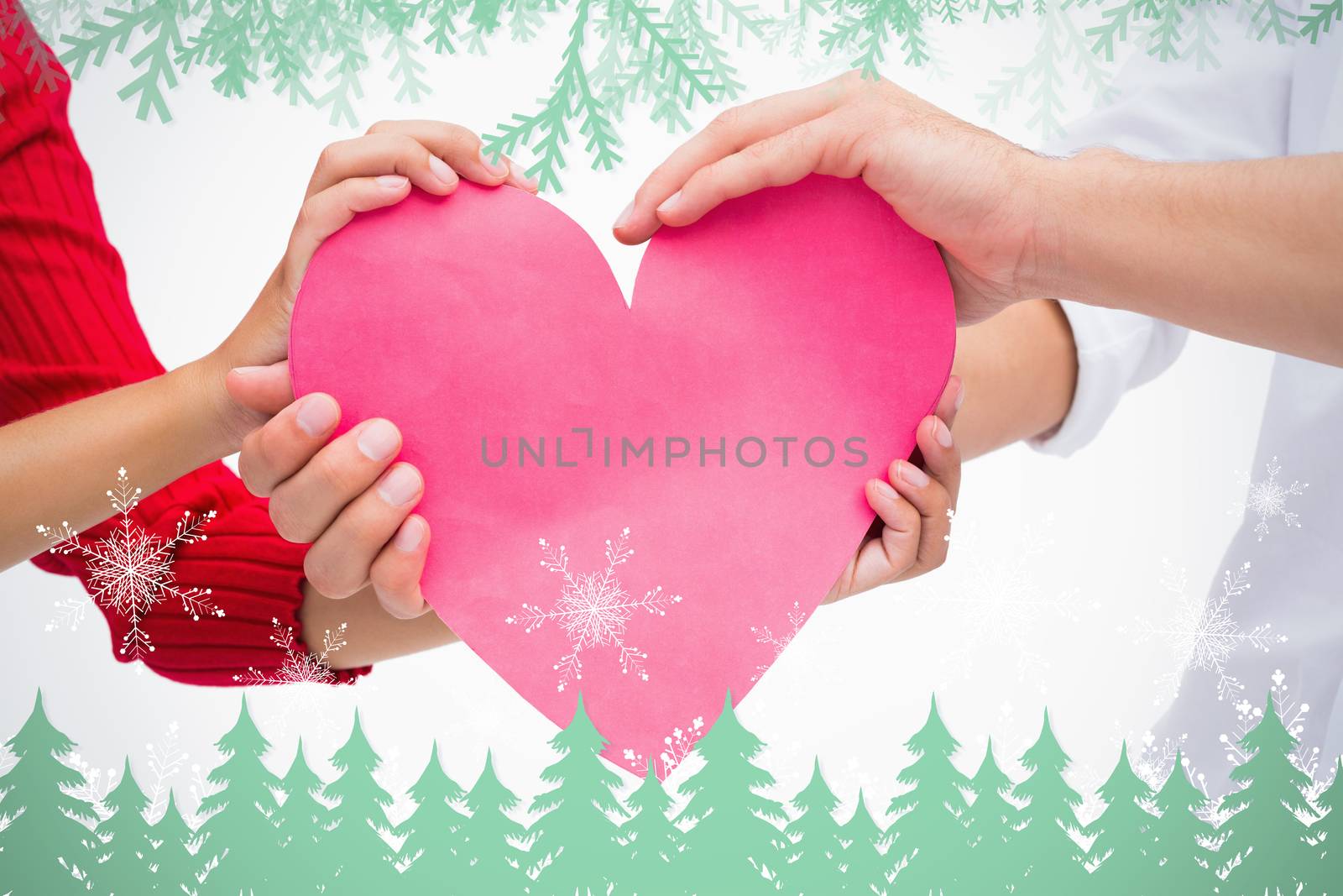 Composite image of Couples hands holding pink heart with frost and fir trees in green