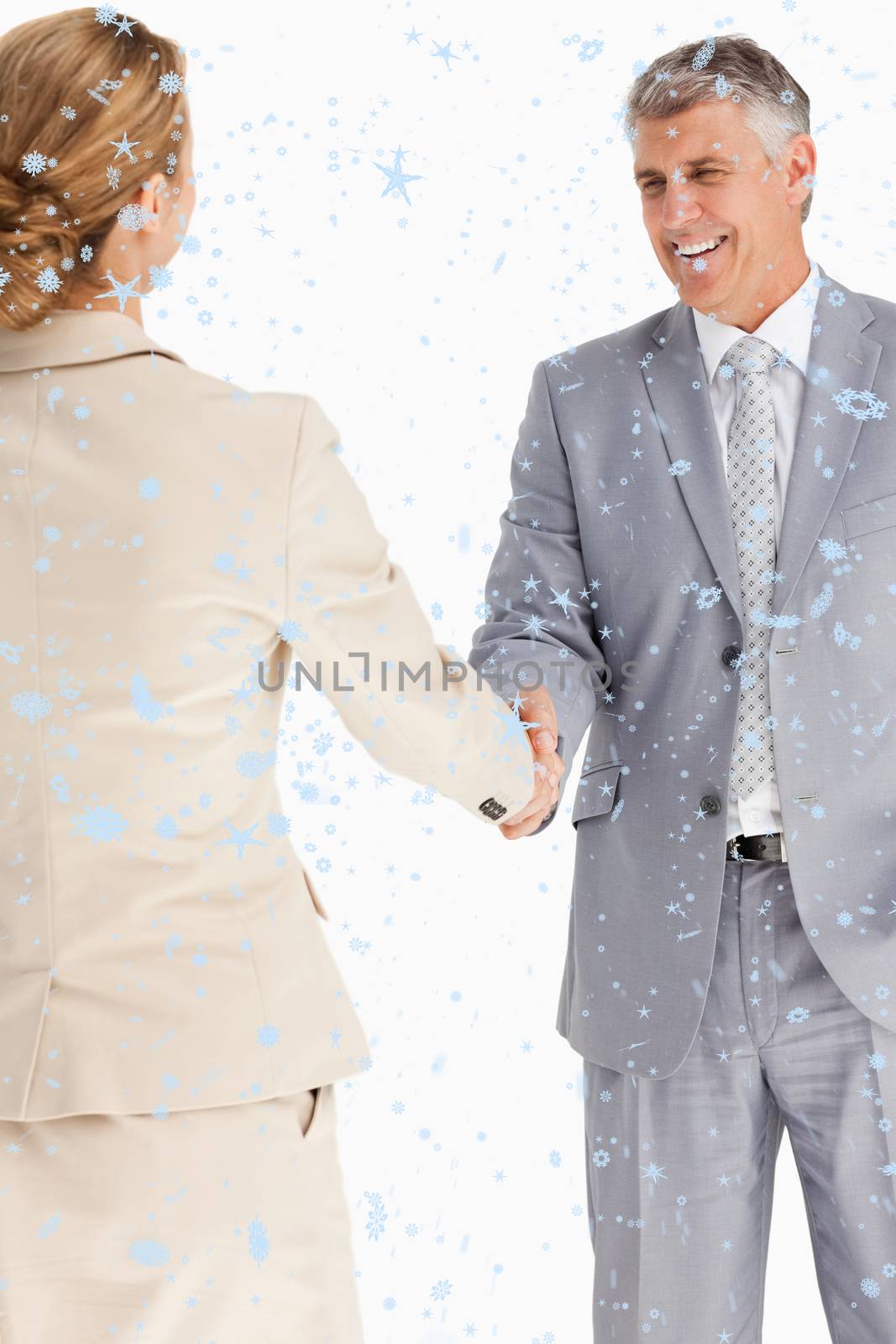 Composite image of Happy business people shaking hands with snow falling