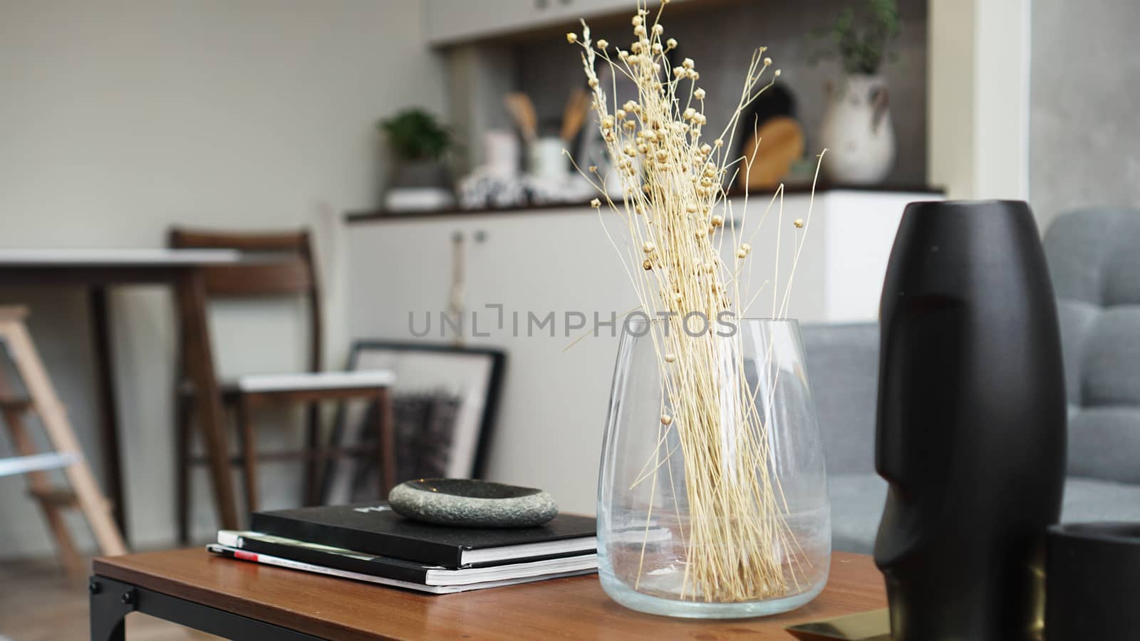 A vase with dry flowers on a table. Scandinavian classic room with wooden and white details, minimalistic interior design. Real photo. Cosy home.