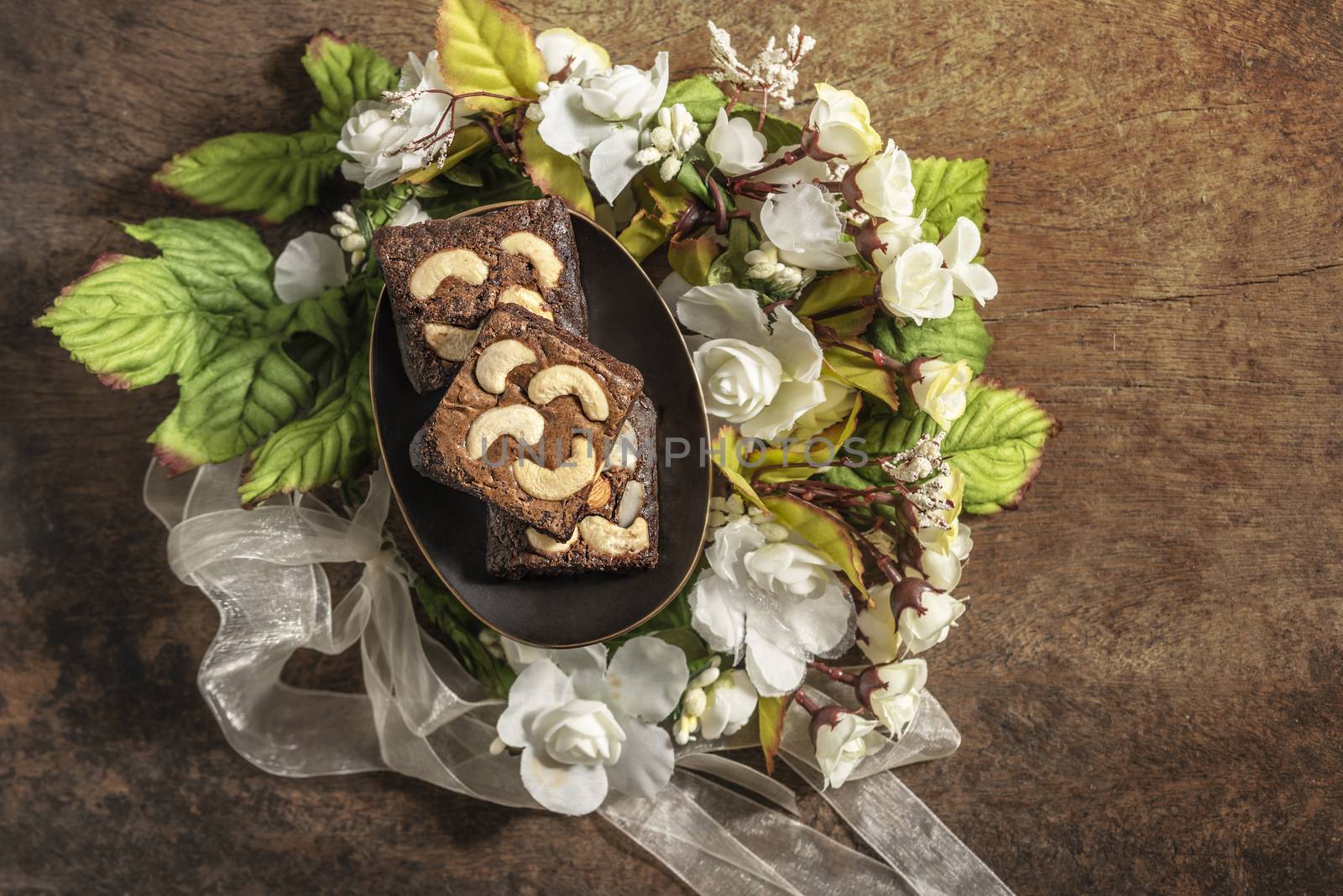 Piece of chocolate cashew nut cake on plate over wooden table