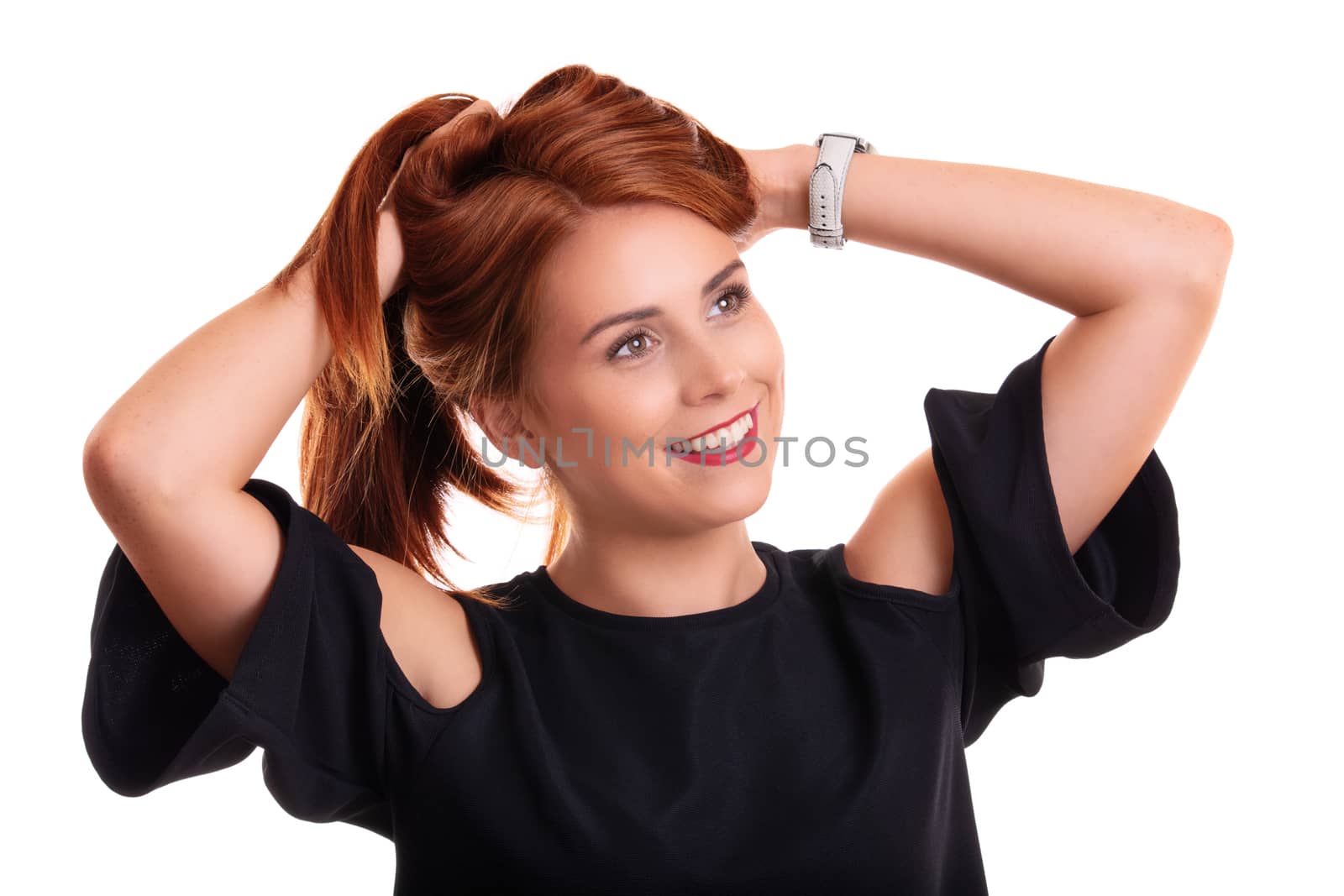 Portrait of a beautiful smiling young redhead woman with hands in her hair, isolated on white background.