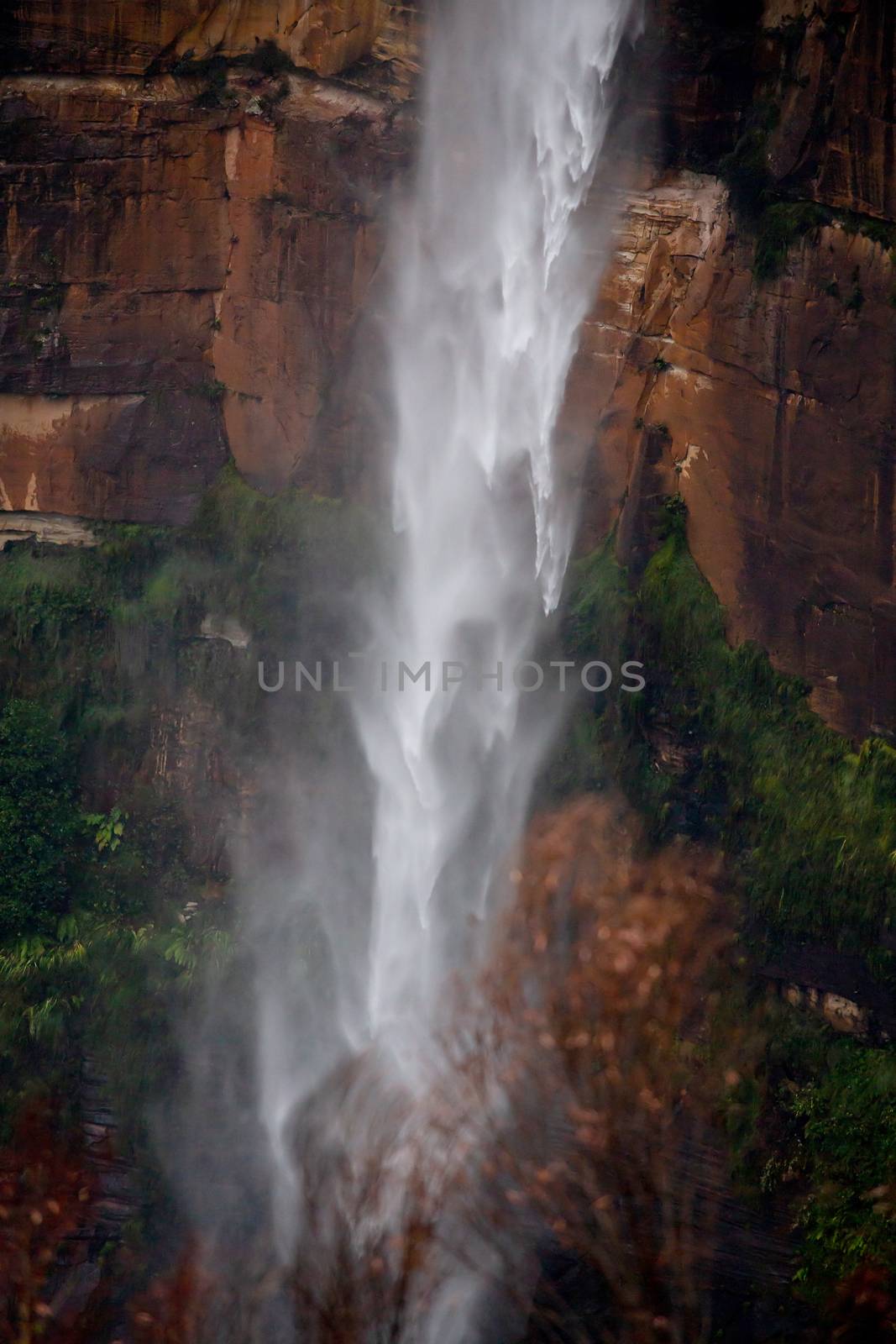 Powerful waterfall tumbling over sandstone cliffs after rain, its movement patterns vary as it falls fast to the bottom