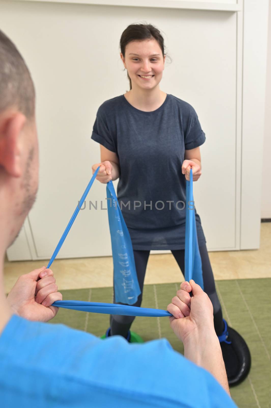 A young male physiotherapist helping a teen girl with stretching exercises 