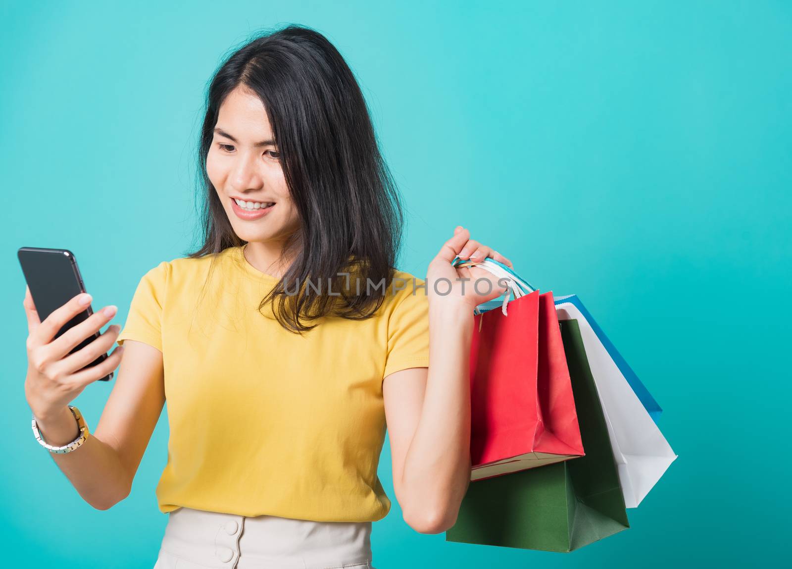 woman smile, She holding shopping bags and using a mobile phone by Sorapop