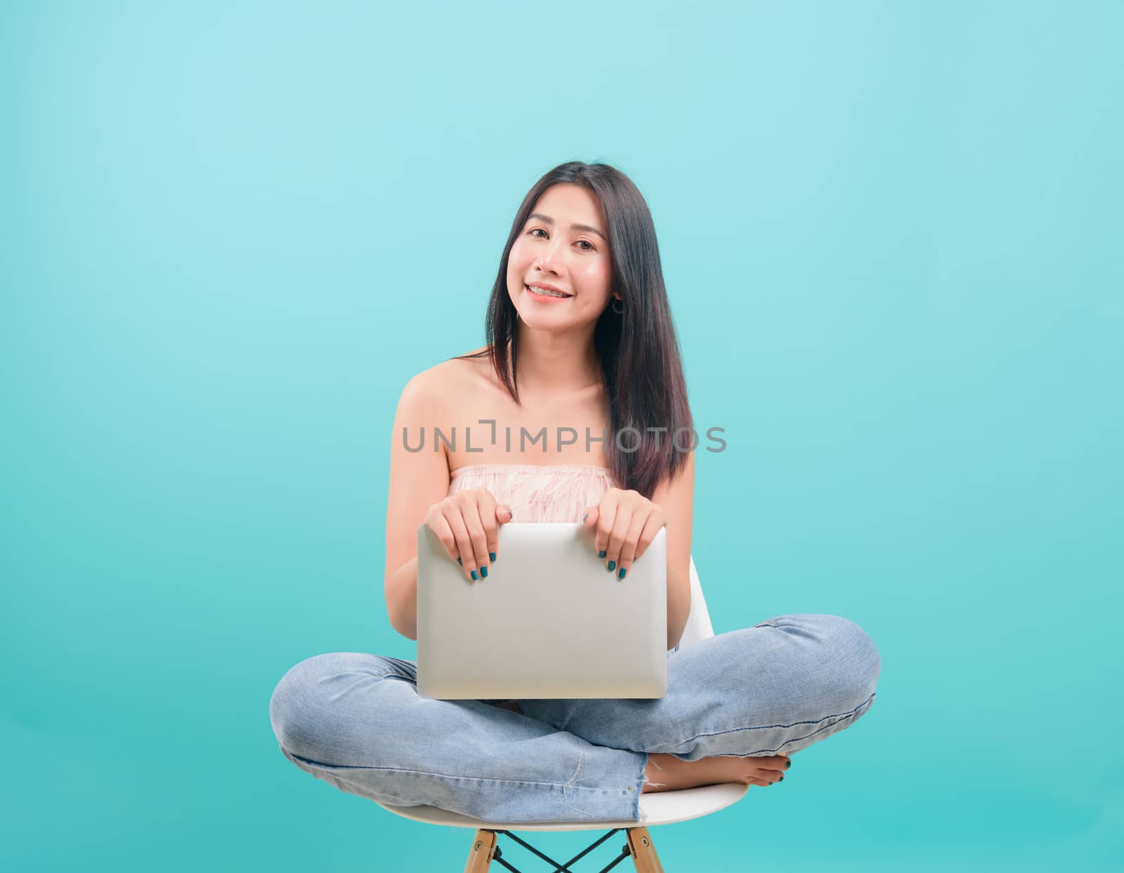 woman sitting on chair smile her  holding laptop computer by Sorapop
