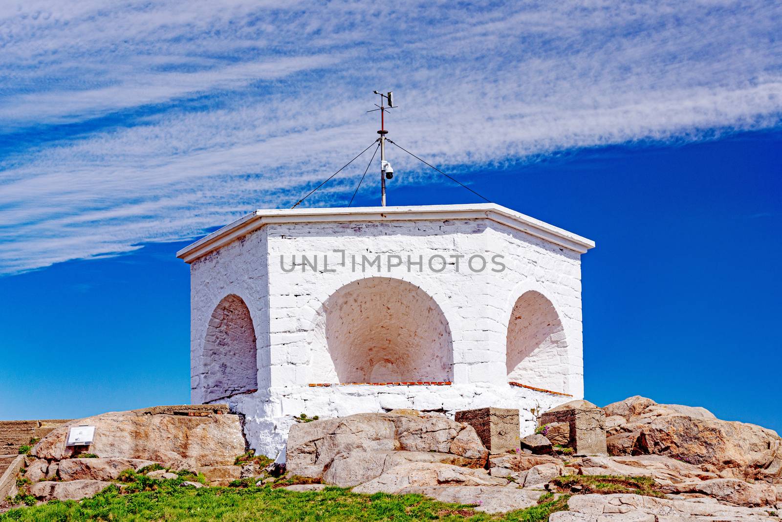 Historic white lighthouse on the edge of rocky sea coast,  Lindesnes, South Norway