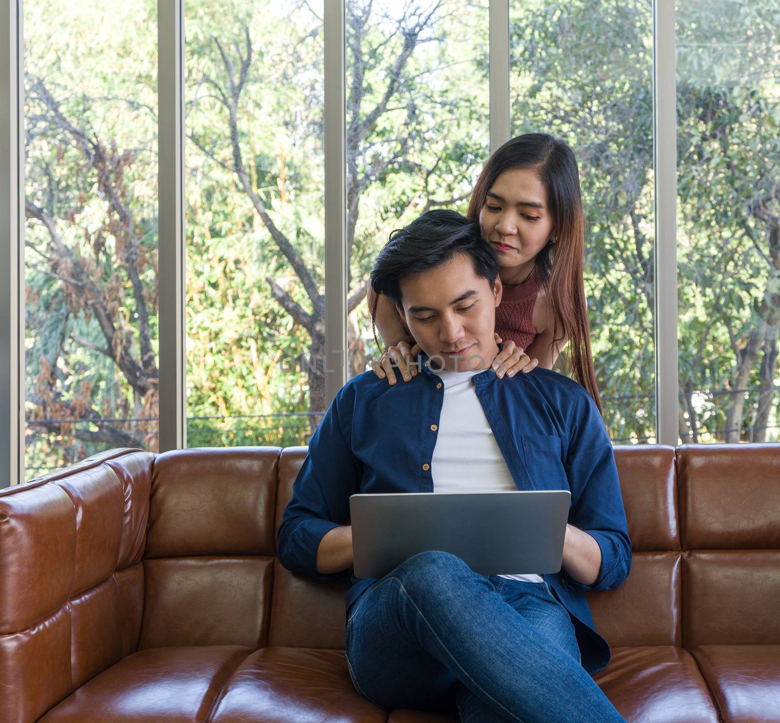 Young lovers spend time together on holidays in the living room. Both of them are interested in internet product information while the man held laptop computer.