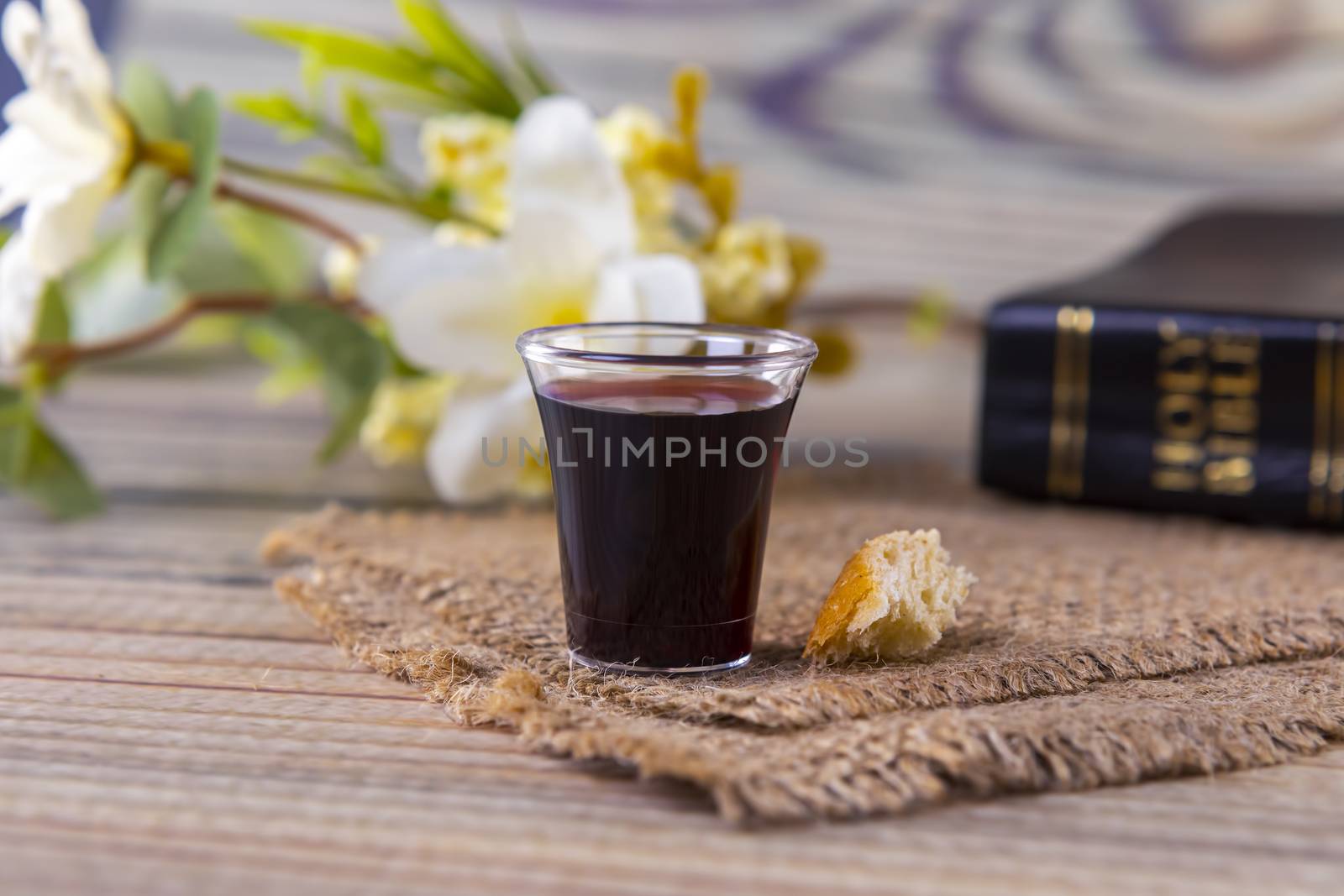 Taking communion concept - the wine and the bread symbols of Jesus Christ blood and body with Holy Bible. Easter Passover and Lord Supper concept Focus on glass.