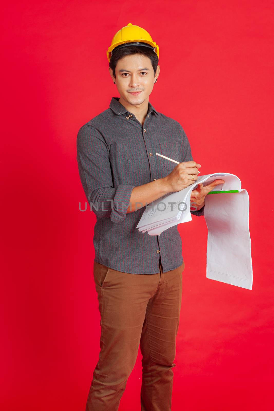 The young civil engineer is considering the construction plan. Portrait people concept on red background