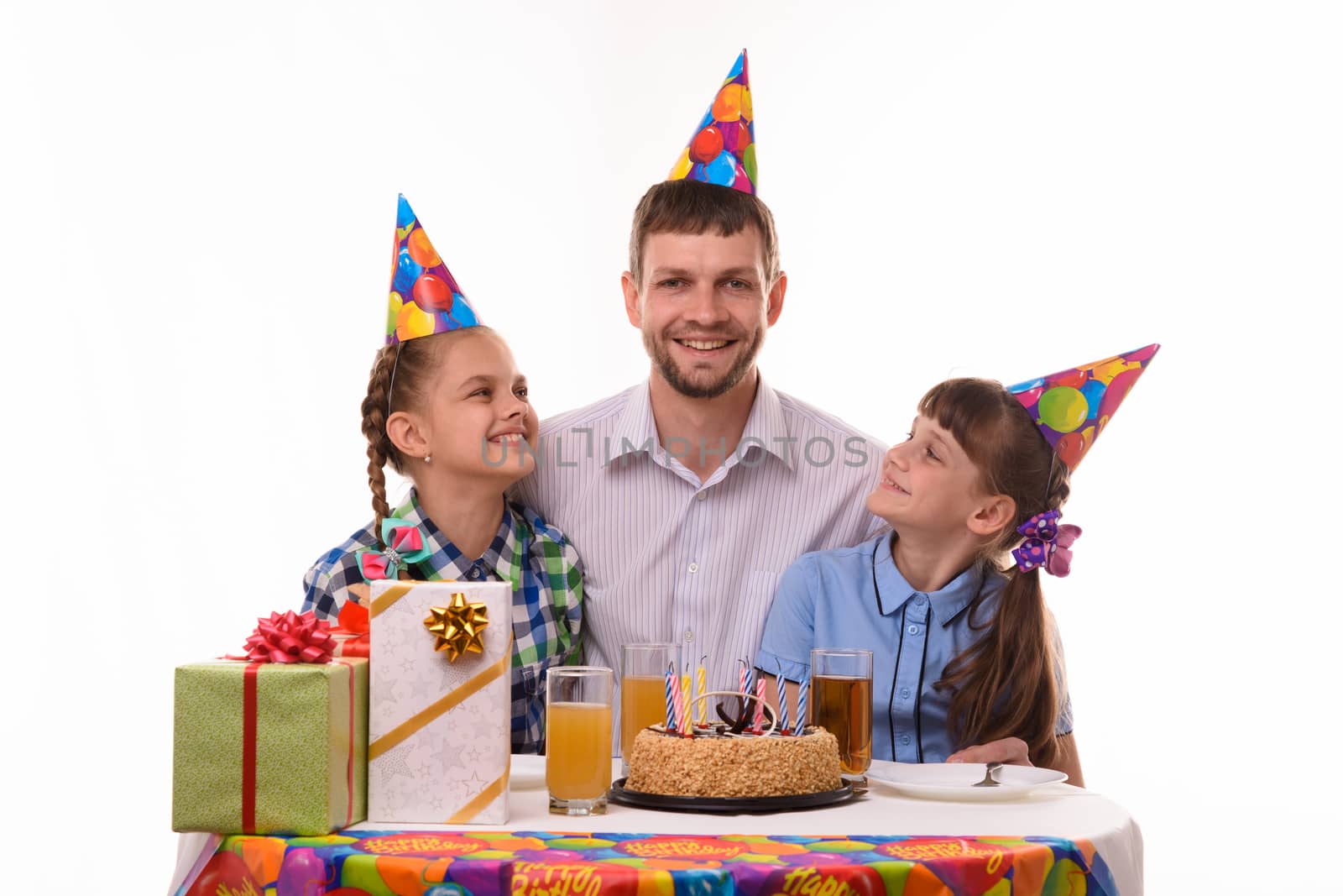 Two girls happily look at dad at the festive table
