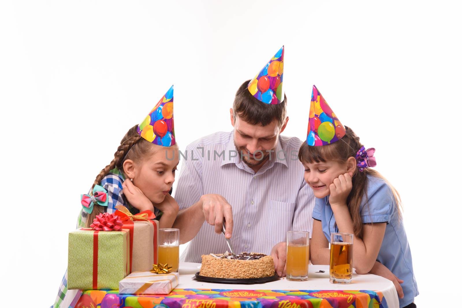 Dad and two daughters cut a birthday cake with a knife