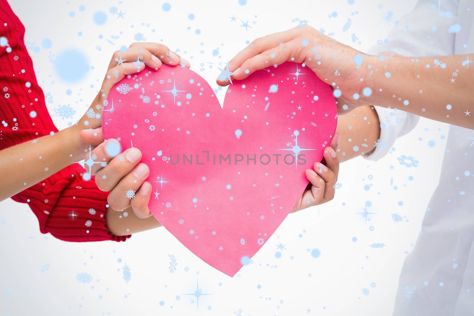 Composite image of Couples hands holding pink heart with snow falling