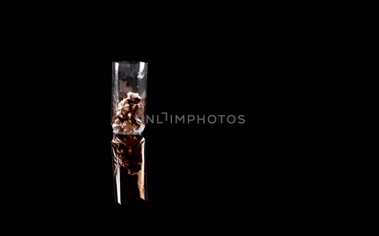 sweets in plastic food packaging with reflection and copy space on black background