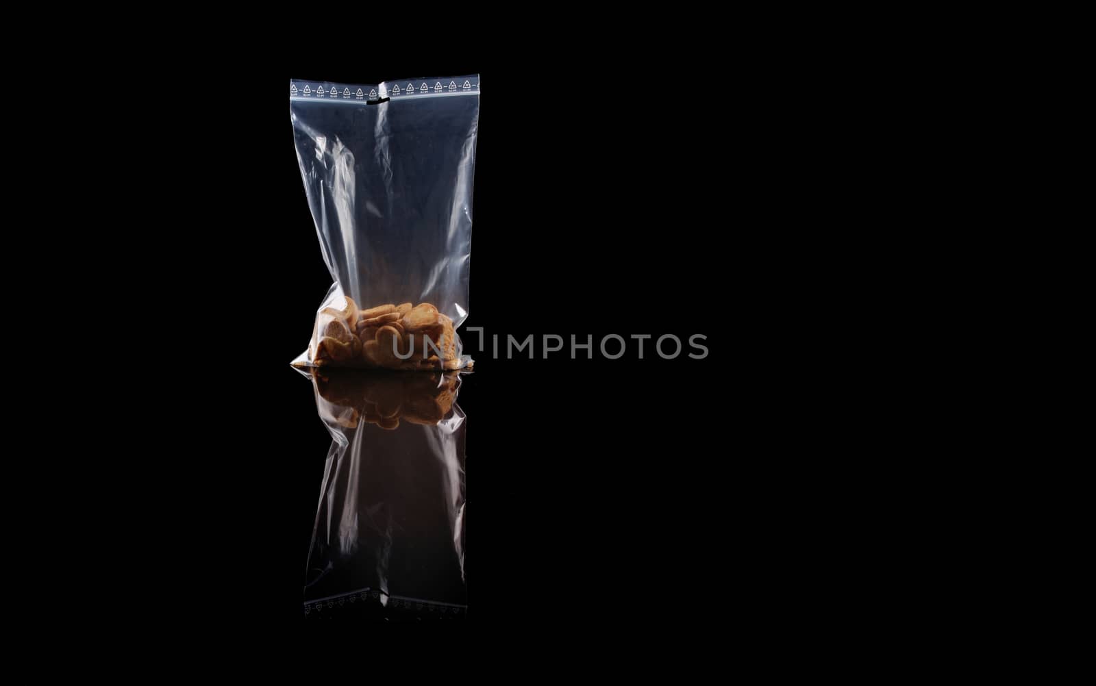 sweets in plastic food packaging with reflection and copy space on black background