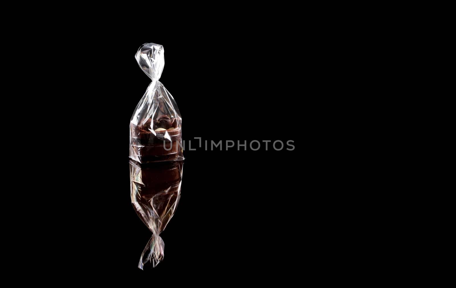 sweets in plastic food packaging with reflection and copy space on black background