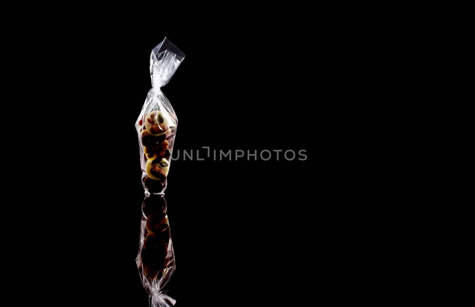 sweets in plastic food packaging with reflection and copy space on black background