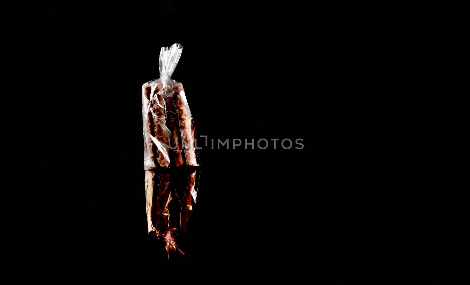 sweets in plastic food packaging with reflection and copy space on black background