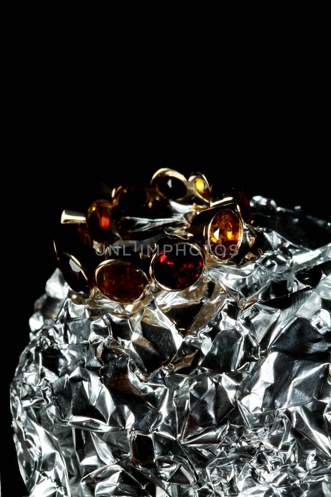 Jewelery with gem stones on tin foil black background with copy space