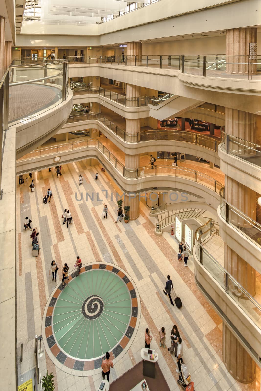 Interior wide view of the Haneda Airport Market Place with a turbine design decoration on floor and atirum on top.