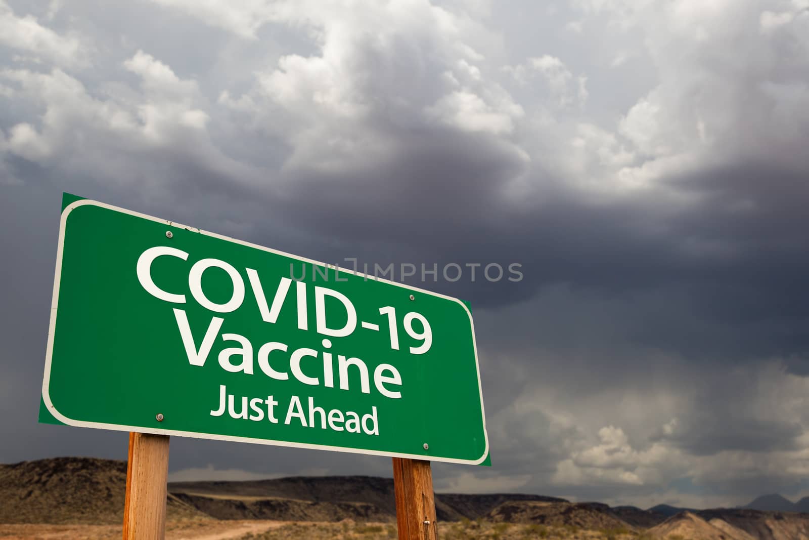 COVID-19 Coronavirus Vaccine Green Road Sign Against Ominous Stormy Cloudy Sky.