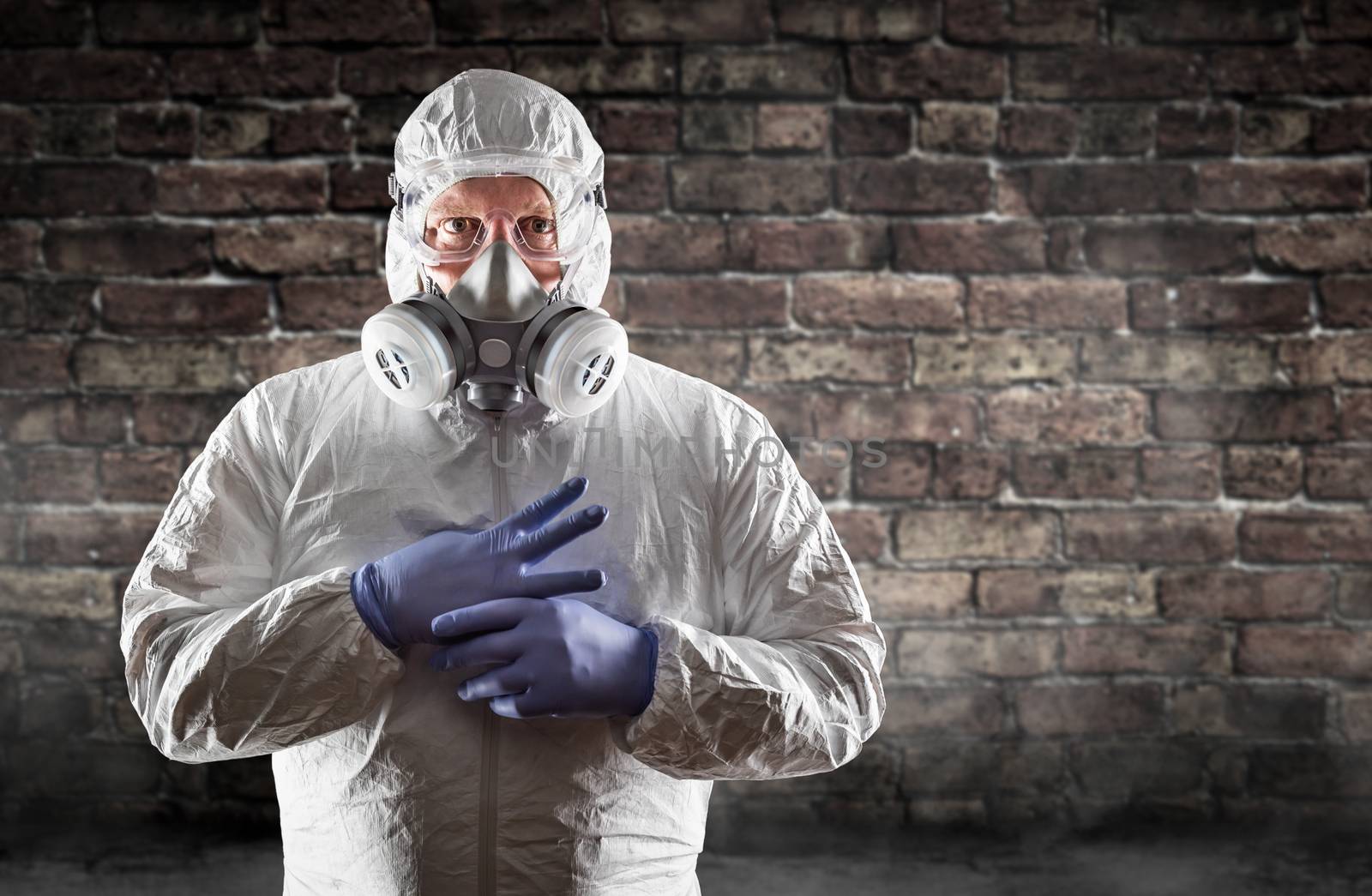 Man Wearing Hazmat Suit, Protective Gas Mask and Goggles Against Brick Wall.