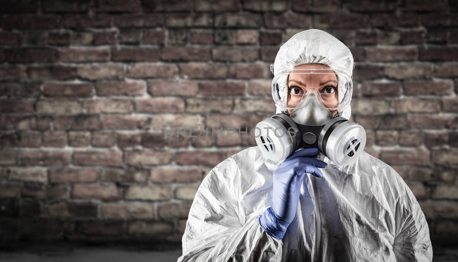 Woman Wearing Hazmat Suit, Protective Gas Mask and Goggles Against Brick Wall. by Feverpitched
