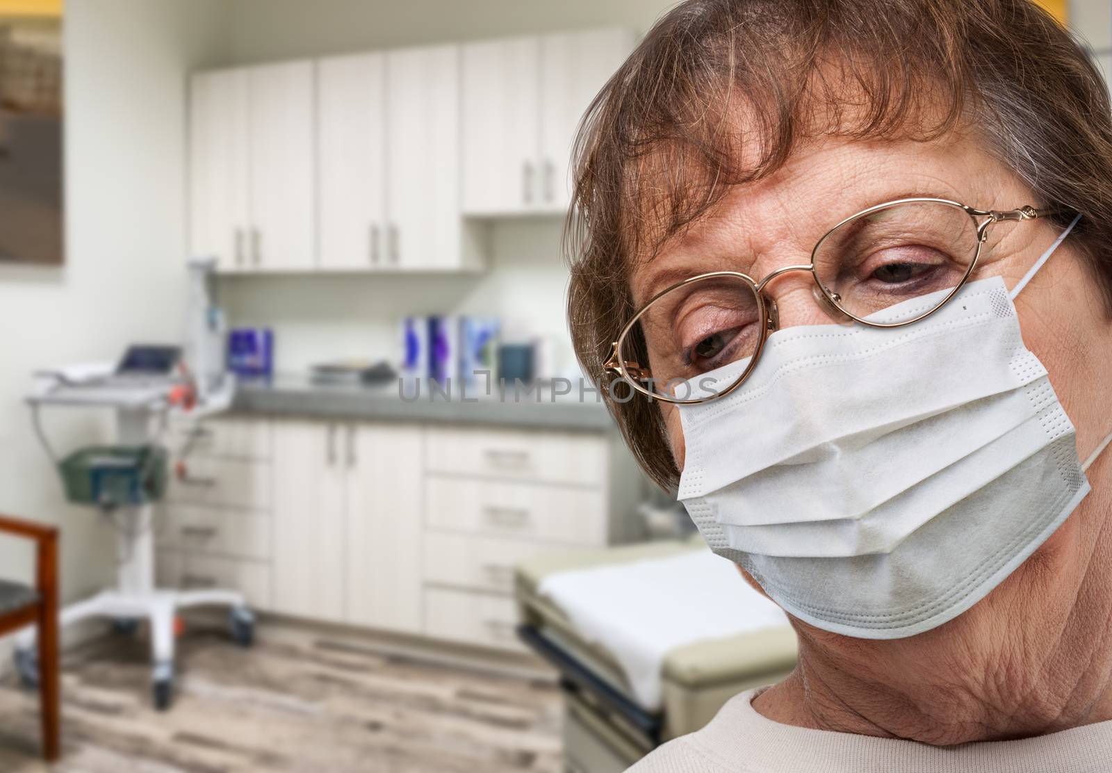 Concerned Senior Adult Woman Wearing Medical Face Mask Waiting In Doctor Office. by Feverpitched