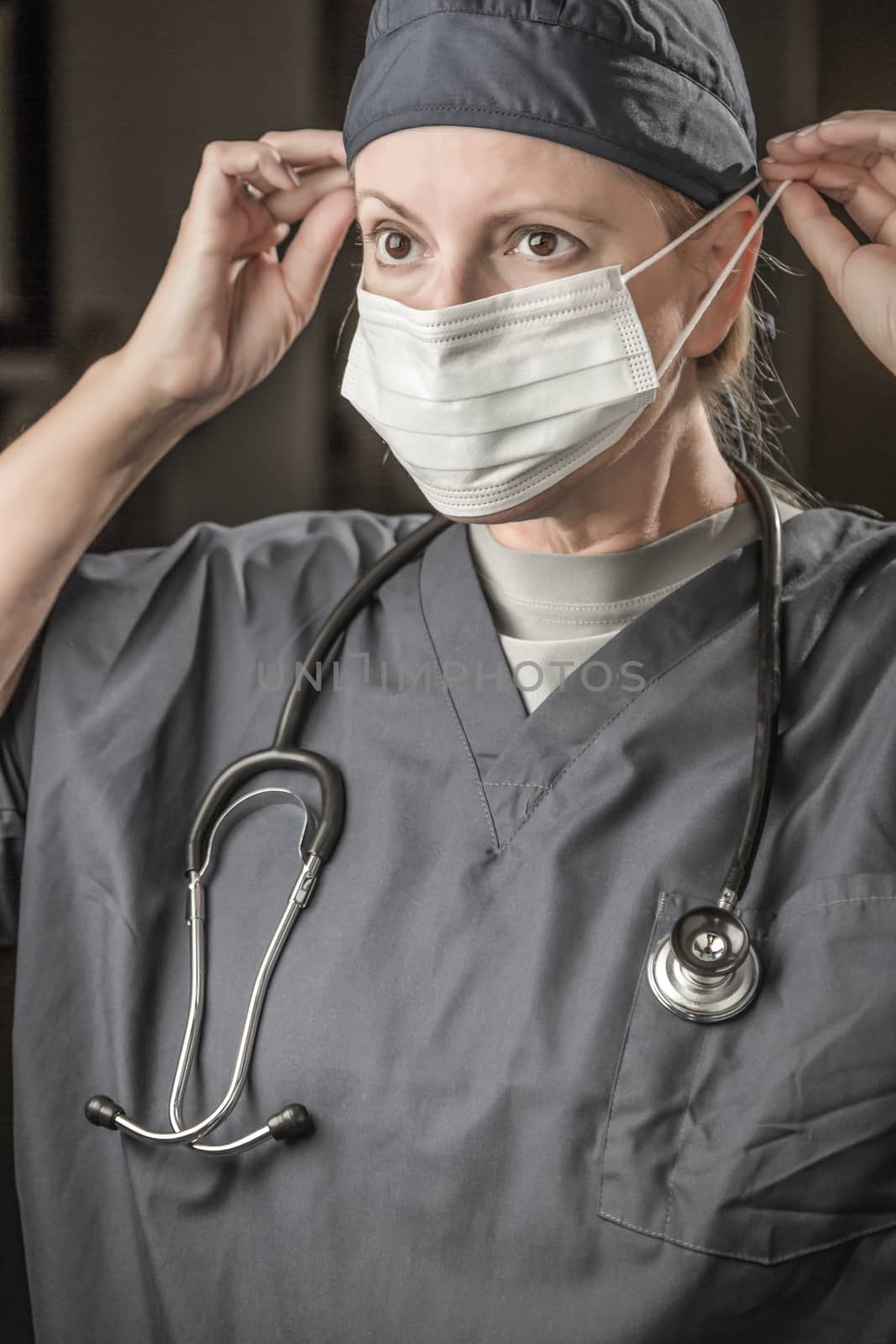 Female Doctor or Nurse with Stethoscope Putting On Protective Face Mask . by Feverpitched