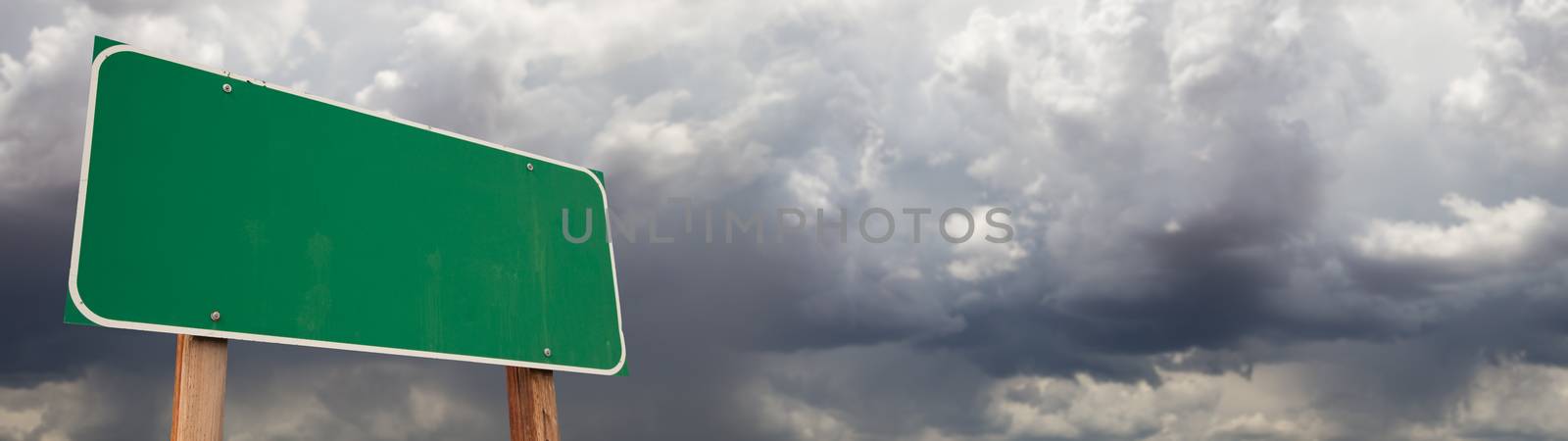Blank Green Road Sign Against Ominous Cloudy Stormy Sky Background Banner.